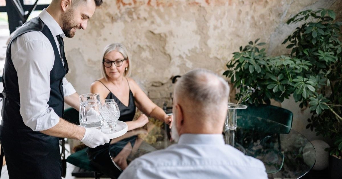 Konobar poslužuje goste u restoranu